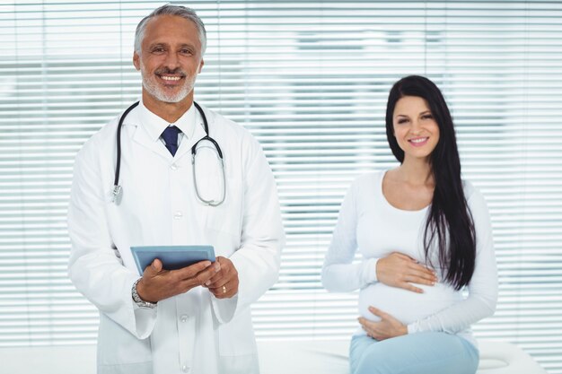 Medico e donna incinta che sorridono alla macchina fotografica in clinica
