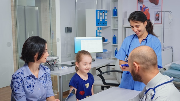 Medico e infermiere che parlano con un bambino paziente seduto alla scrivania in studio medico. Medico sanitario specialista in medicina che fornisce servizi di assistenza sanitaria esame radiografico in ospedale