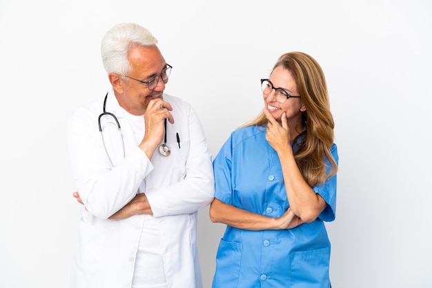 Medico e infermiere di mezza età isolati su sfondo bianco guardandosi l'un l'altro