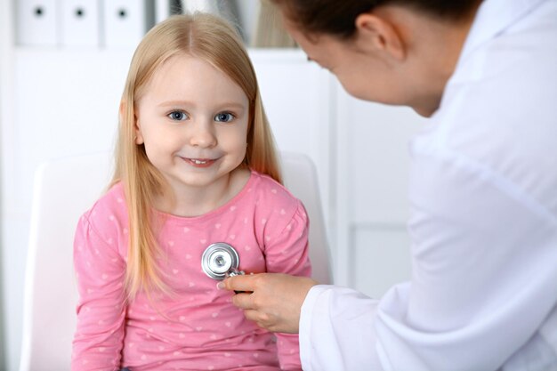 Medico e paziente in ospedale Bambino esaminato dal medico con lo stetoscopio