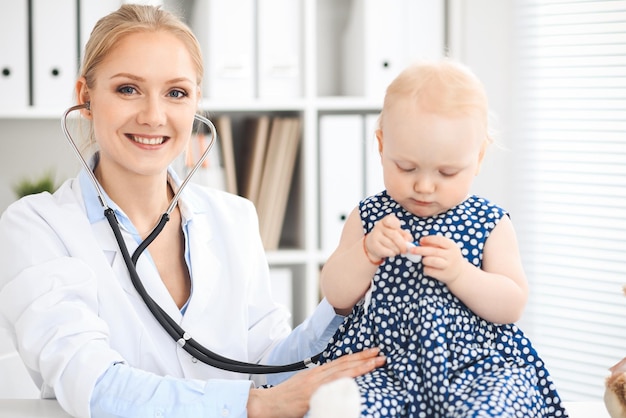 Medico e paziente in ospedale. La bambina vestita in abito blu scuro viene esaminata dal medico con lo stetoscopio. Concetto di medicina e assistenza sanitaria.