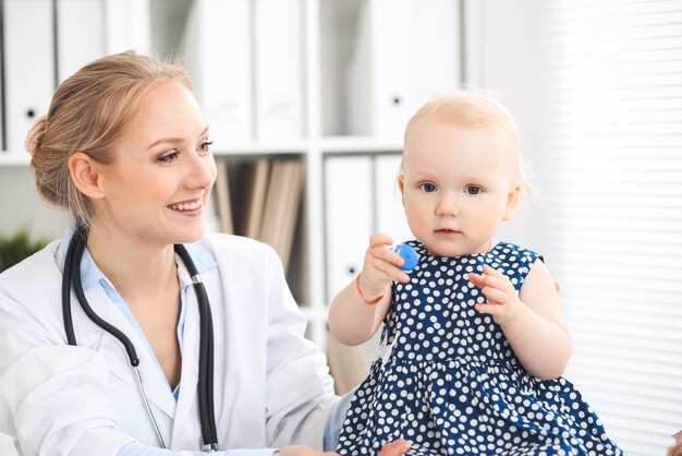 Medico e paziente in ospedale. La bambina vestita in abito blu scuro viene esaminata dal medico con lo stetoscopio. Concetto di medicina e assistenza sanitaria.