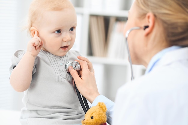 Medico e paziente in ospedale. La bambina vestita in abito grigio viene esaminata dal medico con lo stetoscopio. Concetto di medicina.