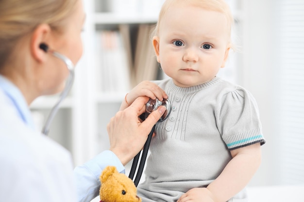 Medico e paziente in ospedale. La bambina vestita in abito grigio viene esaminata dal medico con lo stetoscopio. Concetto di medicina.