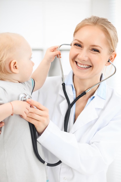 Medico e paziente in ospedale. La bambina vestita in abito grigio viene esaminata dal medico con lo stetoscopio. Concetto di medicina.