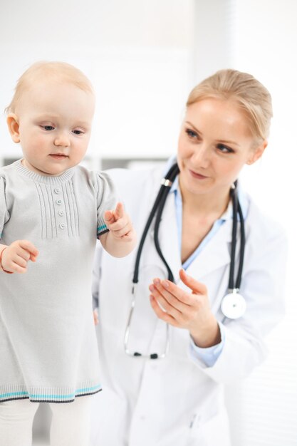 Medico e paziente in ospedale. La bambina vestita in abito grigio viene esaminata dal medico con lo stetoscopio. Concetto di medicina.