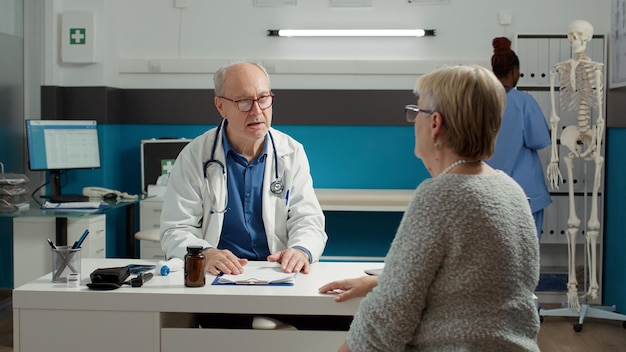 Medico e paziente in pensione che parlano del recupero alla visita di controllo, esaminano la persona per somministrare medicinali e cure su prescrizione. Medico e donna senior che fanno la consultazione di malattia.