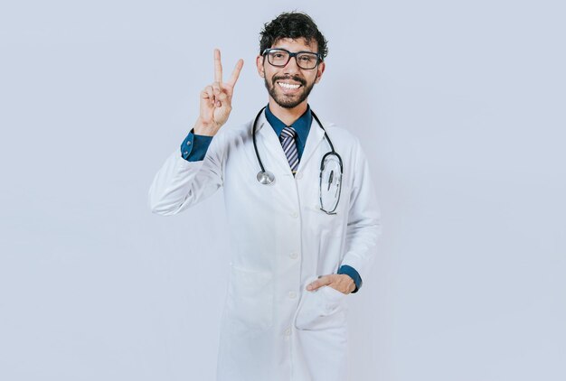 Medico felice che saluta con due dita isolate Medico sorridente che fa gesto di amore e pace isolato