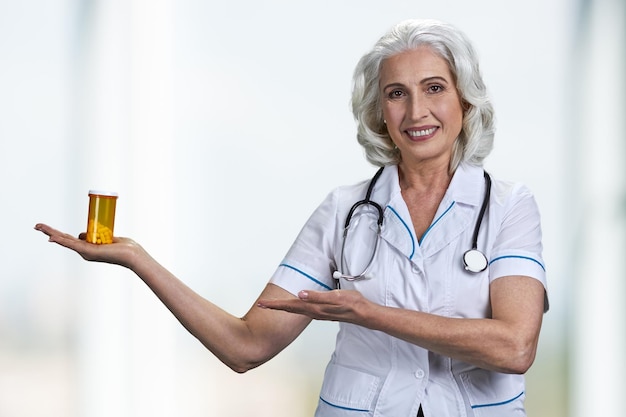 Medico felice della donna matura che mostra bottiglia delle pillole.