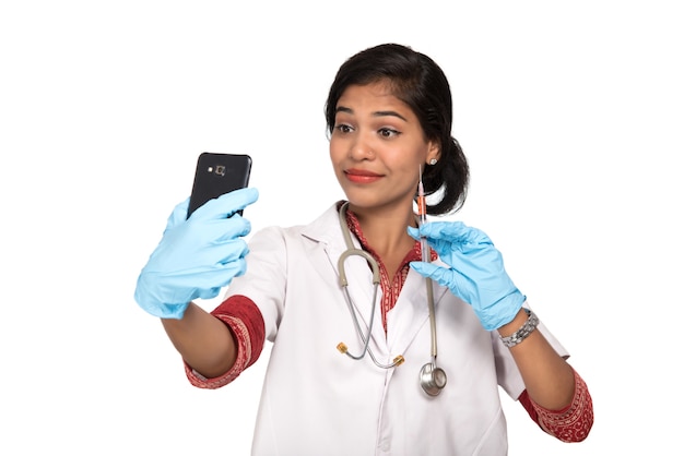 Medico femminile che cattura selfie con lo stetoscopio e l'iniezione tramite smartphone.