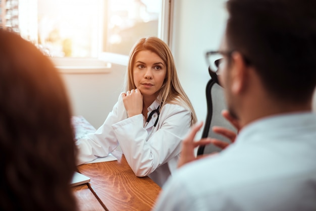 Medico femminile che consulta la giovane coppia nella stanza del medico.