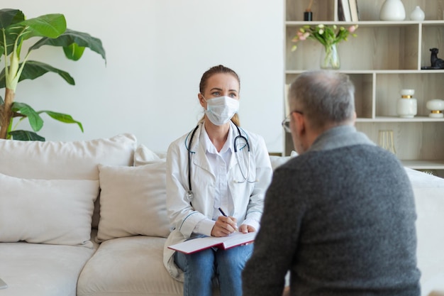 Medico femminile che esamina l'uomo anziano più anziano nell'ufficio del medico oa casa il paziente e il medico del vecchio hanno