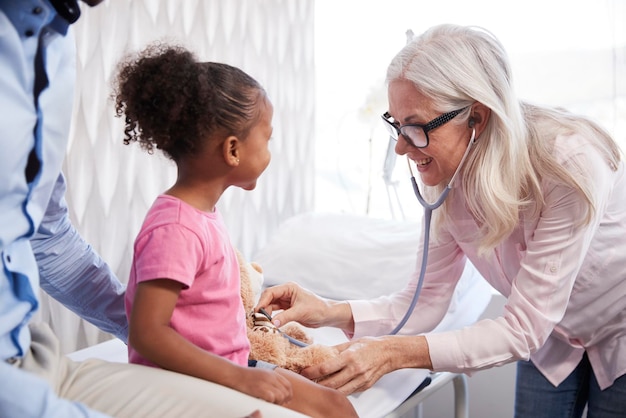 Medico femminile che fa visita medica all'orsacchiotto sulla consultazione della famiglia in ufficio