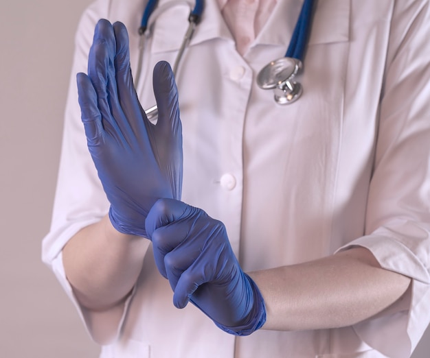 Medico femminile che indossa guanti di gomma protettivi primo piano mani in guanti monouso blu da vicino