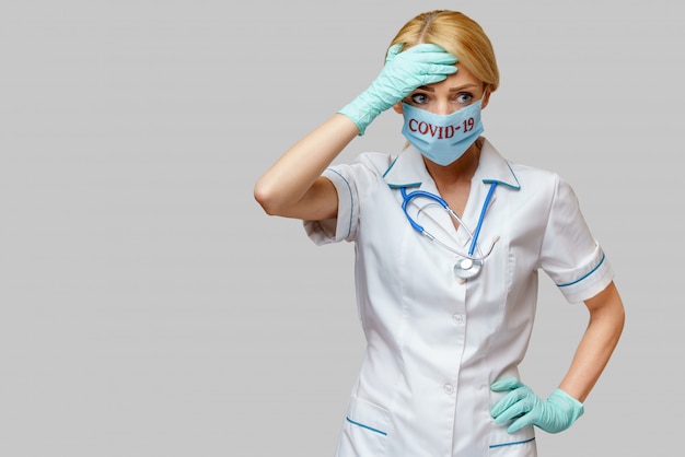 Medico femminile che indossa maschera protettiva e guanti di gomma o in lattice mal di testa e stress