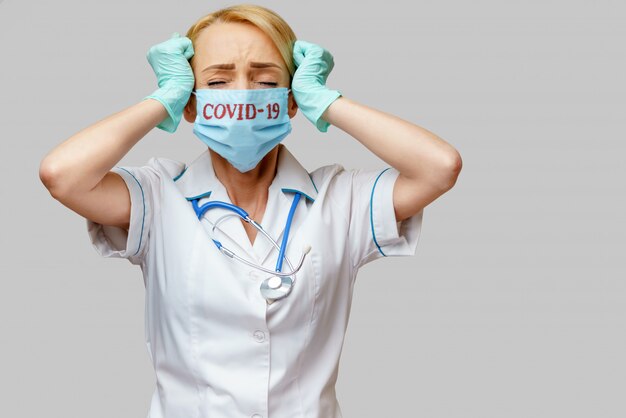 Medico femminile che indossa maschera protettiva e guanti di gomma o in lattice mal di testa e stress