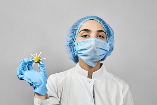 Medico femminile che indossa un'uniforme medica protettiva che tiene coronavirus