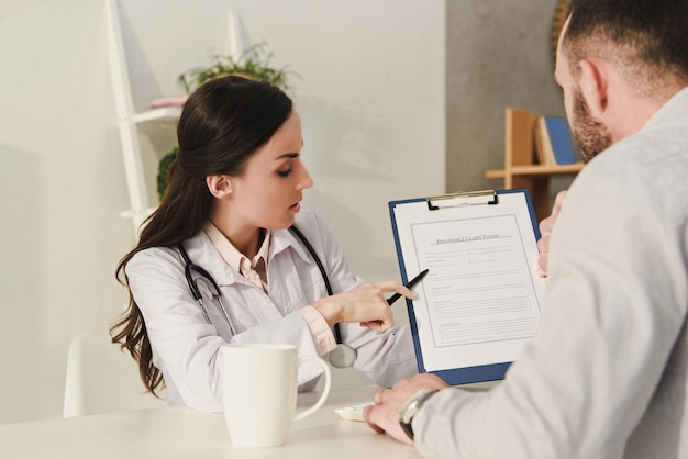 Medico femminile che mostra il modulo di richiesta di assicurazione al cliente