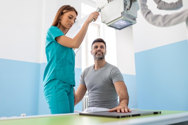 Medico femminile che prende in mano i raggi X dell'uomo in ospedale Il radiologo sta operando la macchina a raggi X Uomo in cura in clinica