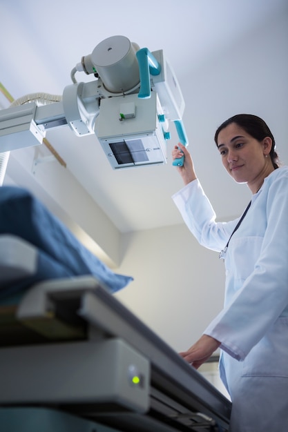 Medico femminile che regola la macchina di raggi x durante l'esame