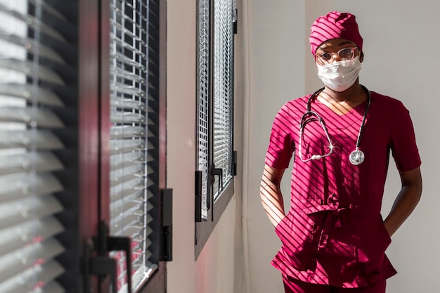 Medico femminile che sta accanto alle finestre dell'ospedale