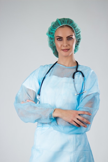 Medico femminile Chirurgo in scrub con cappello medico attraversato le braccia