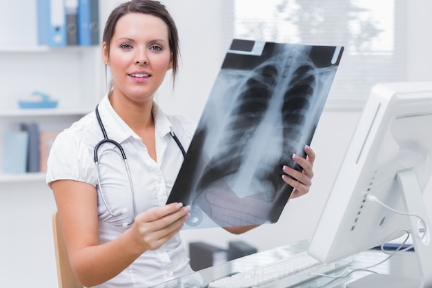 Medico femminile con i raggi X che si siede davanti al computer alla clinica