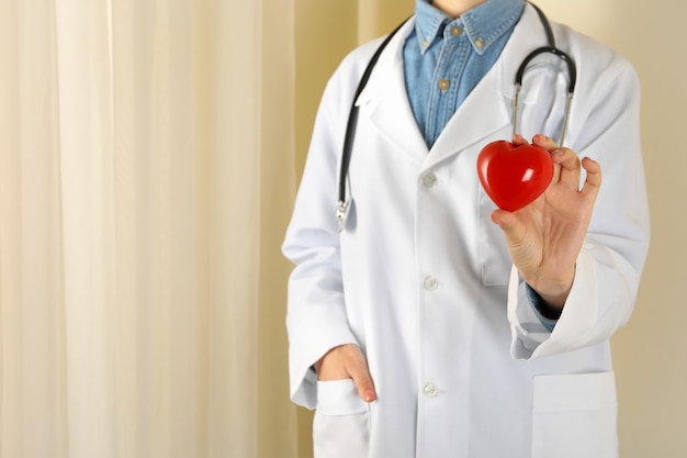 Medico femminile con lo stetoscopio che tiene cuore rosso