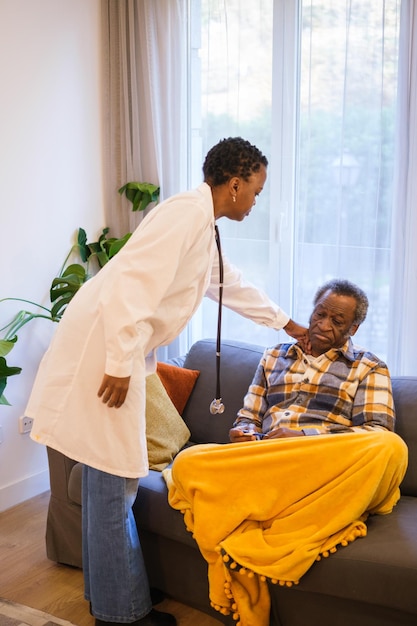 Medico femminile dai capelli corti che ispeziona il suo paziente uomo anziano in pensione che è malato Concetto di assistenza sanitaria malattia del medico in viaggio