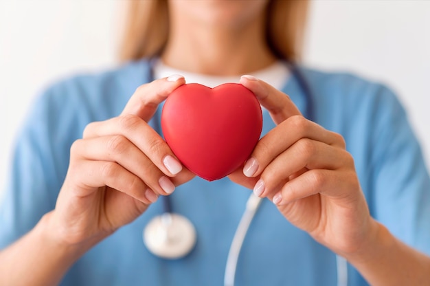 Medico femminile defocused che tiene forma del cuore