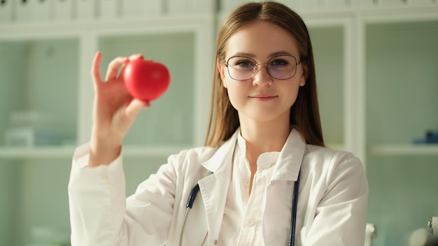 Medico femminile felice del cardiologo che tiene in mano la figura del cuore