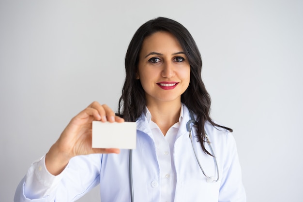 Medico femminile grazioso sorridente che mostra biglietto da visita