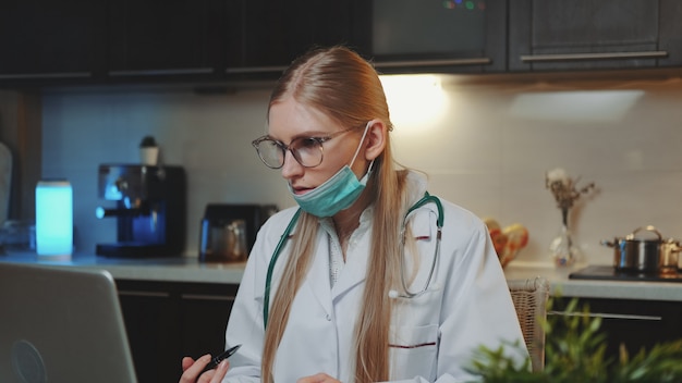 Medico femminile in abito medico che fa videochiamata al paziente da casa