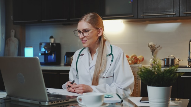 Medico femminile in abito medico che fa videochiamata al paziente da casa