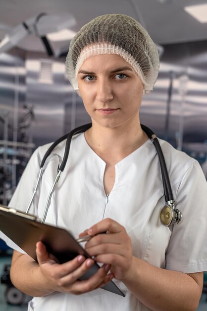 Medico femminile in camice bianco che mostra appunti in bianco per scrivere per registrare la diagnosi del paziente nella moderna sala operatoria dei medici di medicina della sala clinica