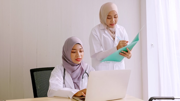 Medico femminile musulmano e assistenti medici che lavorano insieme alla stanza di ospedale.