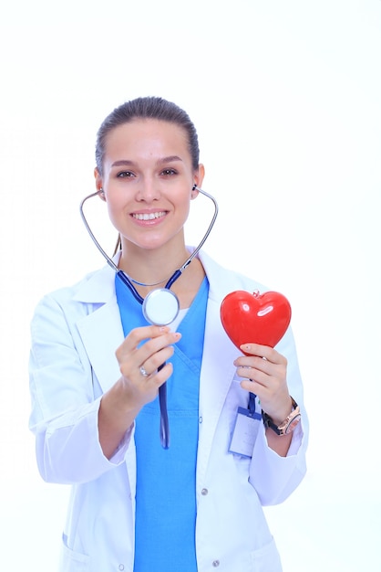 Medico femminile positivo in piedi con lo stetoscopio e il simbolo del cuore rosso isolato Medico donna