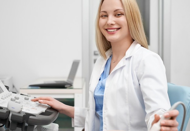 Medico femminile positivo in uniforme bianca che esamina macchina fotografica