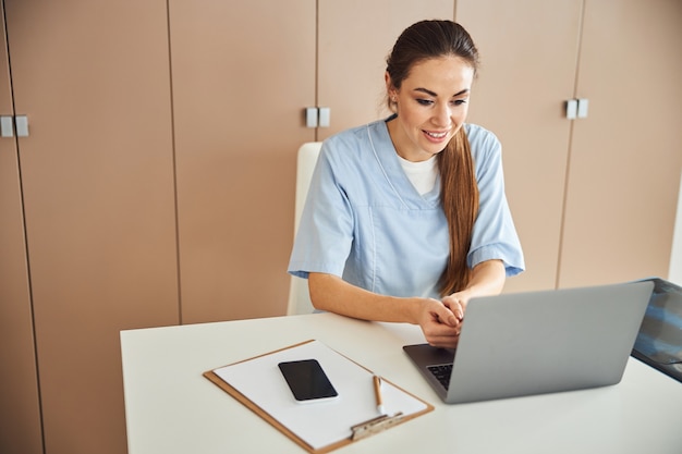 Medico femminile professionista che lavora al suo computer portatile