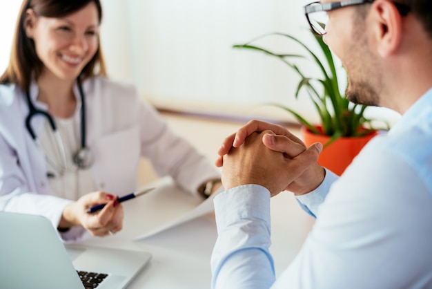 Medico femminile sicuro che discute diagnosi con il paziente in ufficio