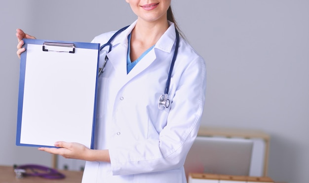 Medico femminile sorridente con una cartella in piedi uniforme Medico femminile sorridente