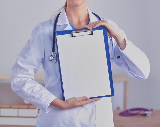 Medico femminile sorridente con una cartella in piedi uniforme Medico femminile sorridente