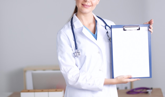 Medico femminile sorridente con una cartella in piedi uniforme Medico femminile sorridente