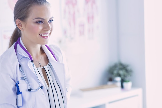 Medico femminile sorridente con uno stetoscopio medico in uniforme in piedi