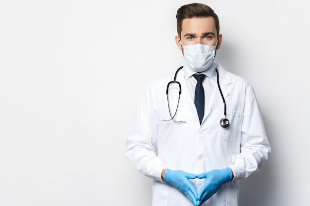 Medico fiducioso con lo stetoscopio che indossa maschera di prevenzione e guanti in lattice