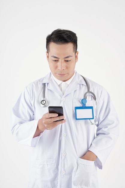 Medico generico in camice che controlla le notifiche sullo smartphone