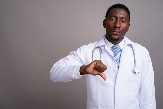 Medico giovane uomo africano bello su sfondo grigio