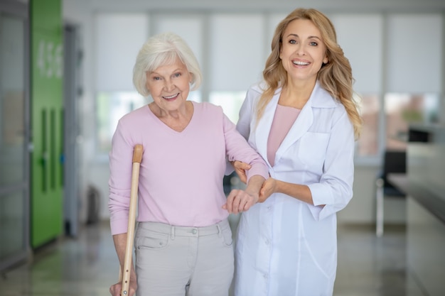 medico in camice da laboratorio che sostiene il suo paziente ed entrambi sorridenti