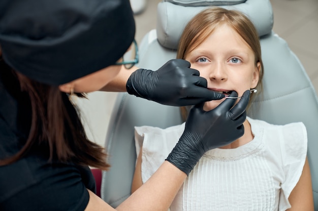 Medico in guanti ispezionando i denti della ragazza.