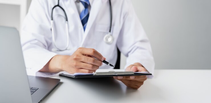 Medico in possesso del file di referto del paziente per valutare i sintomi sulla scrivania.